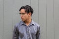 Multiracial young man in eyeglasses, profile view with natural hair in dreadlock twists, serious demeanor,