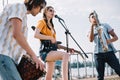Multiracial young people with guitar djembe and saxophone playing music on sunny