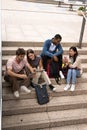 Multiracial young students studying sitting on stairs.Diverse group of happy people reading files outside. Royalty Free Stock Photo