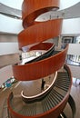 Multistory indoor atrium with suspended wood spiral stairs like dancing ribbon at University of Sydney Business School, Australia