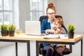 Multitasking businesswoman with her son working at the office Royalty Free Stock Photo