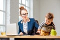 Multitasking businesswoman with her son working at the office Royalty Free Stock Photo