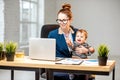 Multitasking businesswoman with her son working at the office Royalty Free Stock Photo