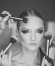 Multitasking. Hands apply makeup on model face. Woman getting powder on skin with brushes, makeup. Woman with young face Royalty Free Stock Photo