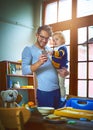 Multitasking is his middle name. a single father using his cellphone and holding his son at home. Royalty Free Stock Photo