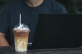 Multitasking man using tablet, Laptop on wooden desk with iced coffee in the cafe Royalty Free Stock Photo