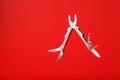 Multitool is a multi-functional tool on a red background. The concept of an open, flying multi-tool with free space Royalty Free Stock Photo