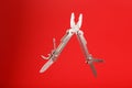 Multitool is a multi-functional tool on a red background. The concept of an open, flying multi-tool with free space Royalty Free Stock Photo