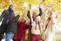 Multl Generation Family Throwing Leaves In Autumn Garden