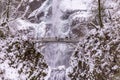 View at a scenic bridge in front of a waterfall covered in snow