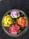 Multy colour artificial flower with transparent round flower vase for home decorating.