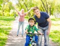 Mum and dad taught his son to ride a bicycle in the park