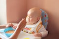 Mum is feeding porridge spoon small child stool Royalty Free Stock Photo