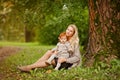 Mum gently embraces the redhead baby girl on autumn forest background Royalty Free Stock Photo