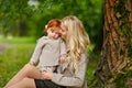 Mum gently embraces the redhead baby girl on autumn forest background Royalty Free Stock Photo