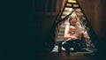 Mum and her little daughter read a book together in a teepee in the evening Royalty Free Stock Photo