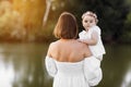 Mum with little daughter outdoors on summer. Young mother with baby girl walk on beach near lake. Family holiday on pond Royalty Free Stock Photo