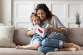 Mother and daughter sitting on couch holding postcard reading wishes