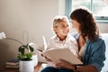 Mum makes learning to read fun. an adorable little girl reading a book together with her mother on the sofa at home. Royalty Free Stock Photo