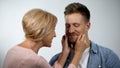 Mum pinching adult son cheeks, male smiling, overprotection effect concept Royalty Free Stock Photo