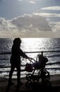 Mum with pram walking along sea front silhouettte Royalty Free Stock Photo