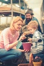 Mum showing her son tender leaves of small flower in hot pink pot while holding gardening spade. Family working together