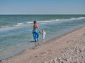 Mum and son are walking along the beach. Young mother with kid little boy are on the seaside. Happy family and happy Royalty Free Stock Photo