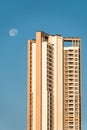 A high rise skyscraper with a moon in the sky above in the city of Mumbai