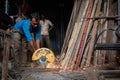 Mumbai,India,August-25-2019:Labourer cutting metal with an electrical metal cutter in local metal shop.There are many such