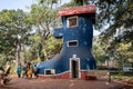 Indian family takes photos in front of the Old Womans Shoe nursery rhyme tourist attraction at