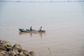 Two fishermen in a small boat cast netting out to sea to catch fish near Elephanta Island