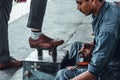 Mumbai, India, 22 november, 2019 / Shoe shiner at work in the train station, cleaning a men`s shoe Royalty Free Stock Photo