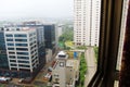 Mumbai rains through the window overlooking office buildings, apartments, roads and green hills