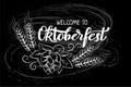 Munich Beer Festival Oktoberfest handwritten text with line art illustration of wheat heads and hop cones. Chalk lettering on blac