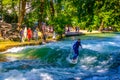 MUNICH, GERMANY, AUGUST 20, 2015: group of surfers is practicing their skill on an artificial wave situated on a small Royalty Free Stock Photo