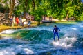 MUNICH, GERMANY, AUGUST 20, 2015: group of surfers is practicing their skill on an artificial wave situated on a small Royalty Free Stock Photo