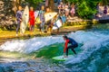 MUNICH, GERMANY, AUGUST 20, 2015: group of surfers is practicing their skill on an artificial wave situated on a small Royalty Free Stock Photo