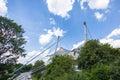 Munich, Germany - July 6, 2022: The roof of the Olympia Stadium through the trees of the Olympic park. The arena is not used by Royalty Free Stock Photo