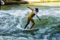 Munich, Germany - July 13, 2021: Surfer in the city river Eisbach. Munich is famous for surfing in urban enviroment