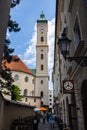 Munich, Germany - July 6, 2022: The tower of the Heiliggeistkirche, view through a narrow street of the old town. An old street
