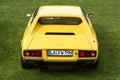 Munich, Germany - September 19, 2015: A rear view of a yellow 1975 Ferrari Dino 308 GT4 classic sports car parked on green grass.