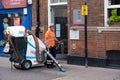 Municipal employee cleans the sidewalk with an electric municipal waste vacuum cleaner