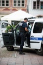 Municipal policeman at phone and police car on the main place