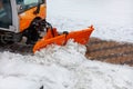 A municipal road sweeper cleans the sidewalk from snow