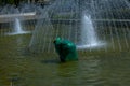 Municipal services adjust the fountains before the summer heat. A cloaked worker repairs a