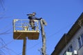 Municipal worker cutting dead standing tree with chainsaw using truck-mounted lift