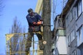 Municipal worker cutting dead standing tree with chainsaw using truck-mounted lift