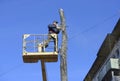 Municipal worker cutting dead standing tree with chainsaw using truck-mounted lift