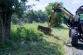 Municipal worker driving using the mechanical mower mowing grass on roadside suburban highway road maintenance service