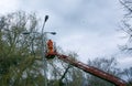 A municipal worker in protective gear replacing bulbs in a street lamp.